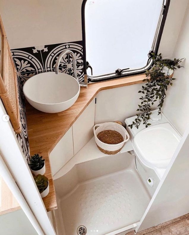 a bathroom with a sink, toilet and mirror in the corner next to a window