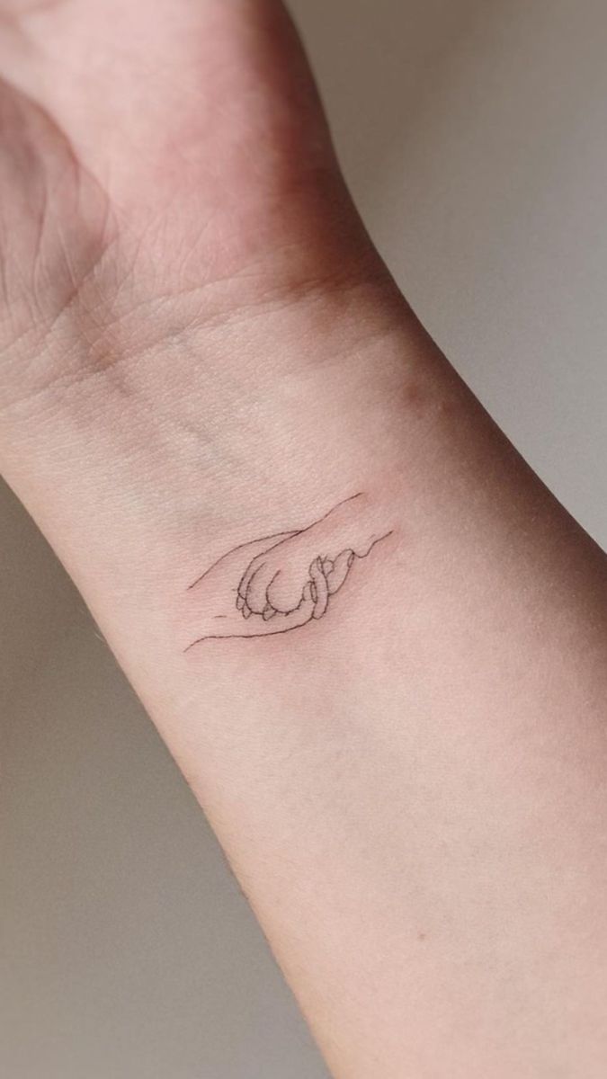 a hand with a small wave tattoo on it's left wrist and the other arm