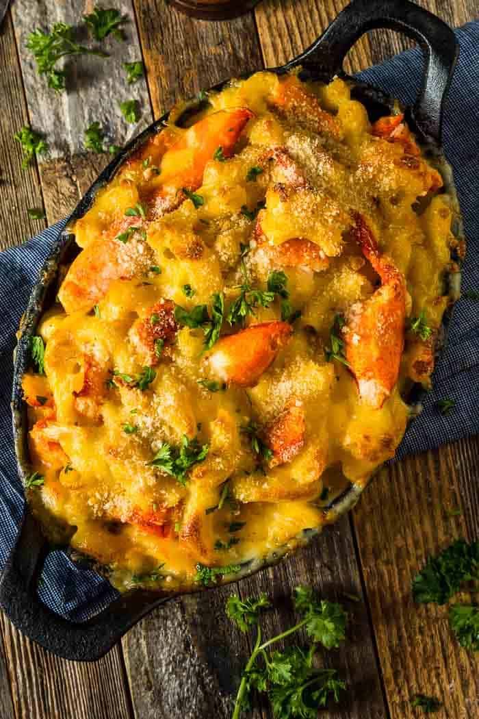 a casserole dish with shrimp and cheese in a cast iron skillet on a wooden table