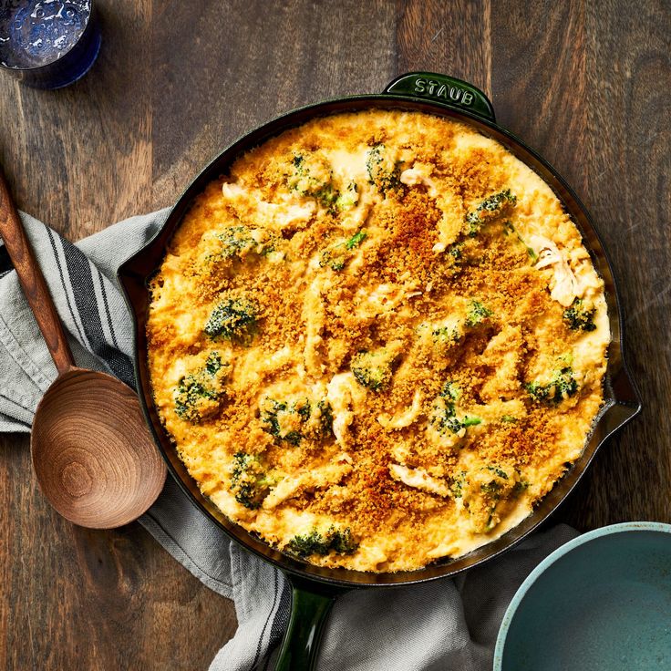 a casserole dish with broccoli and cheese in it on a wooden table