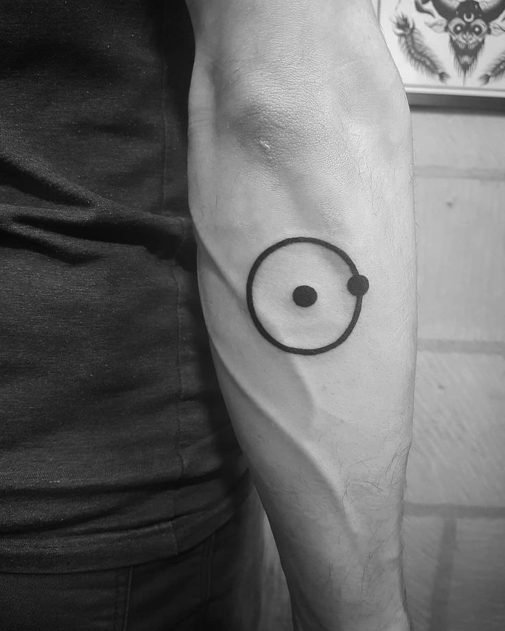 a black and white photo of a man's arm with a circle tattoo on it