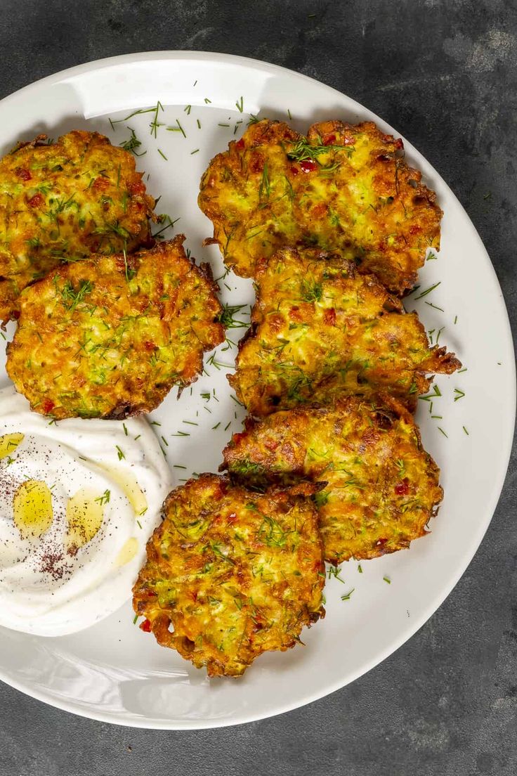 some food is on a white plate next to an egg and yogurt sauce