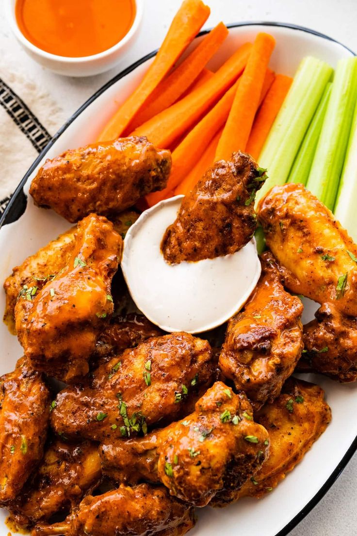 chicken wings, carrots and celery sticks on a plate with dipping sauce