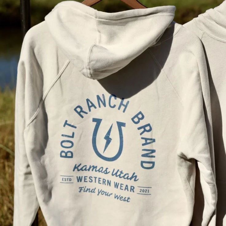 The Bolt Ranch Harvest Collection Adult Hoodie only get better with wear and just the right fit. Get yours today and be ready for fun at the rodeo, in the barn or out on the town. The Harvest Collection Adult Hoodie has the famous Bolt Ranch Bull Head Logo on the front left and the Bolt Ranch Tombstone Logo on the back all in a faded blue print. Features: Double needle stitching at the waistband and cuffs 1x1 Ribbed cuffs Waistband with Spandex Hoodie with strings with Kangaroo Pocket Color: Stone Heather Material: 52% Cotton / 48% Polyester Cute Western Hoodies, Trendy Crew Neck T-shirt For Ranch, Hoodies Western, Southern Fits, Country Sweatshirts Hoodie, Western Hoodies Ranch Dress'n Western Boutique, Bull Head Logo, Western Hoodies, Western Sweatshirts & Hoodies