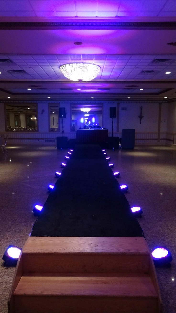 the stairs are lit up with blue lights in an empty room that is decorated with black carpet and wooden steps