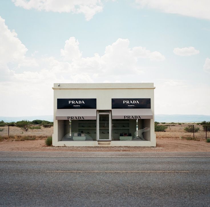 two empty store fronts sitting on the side of an empty road in front of a desert landscape