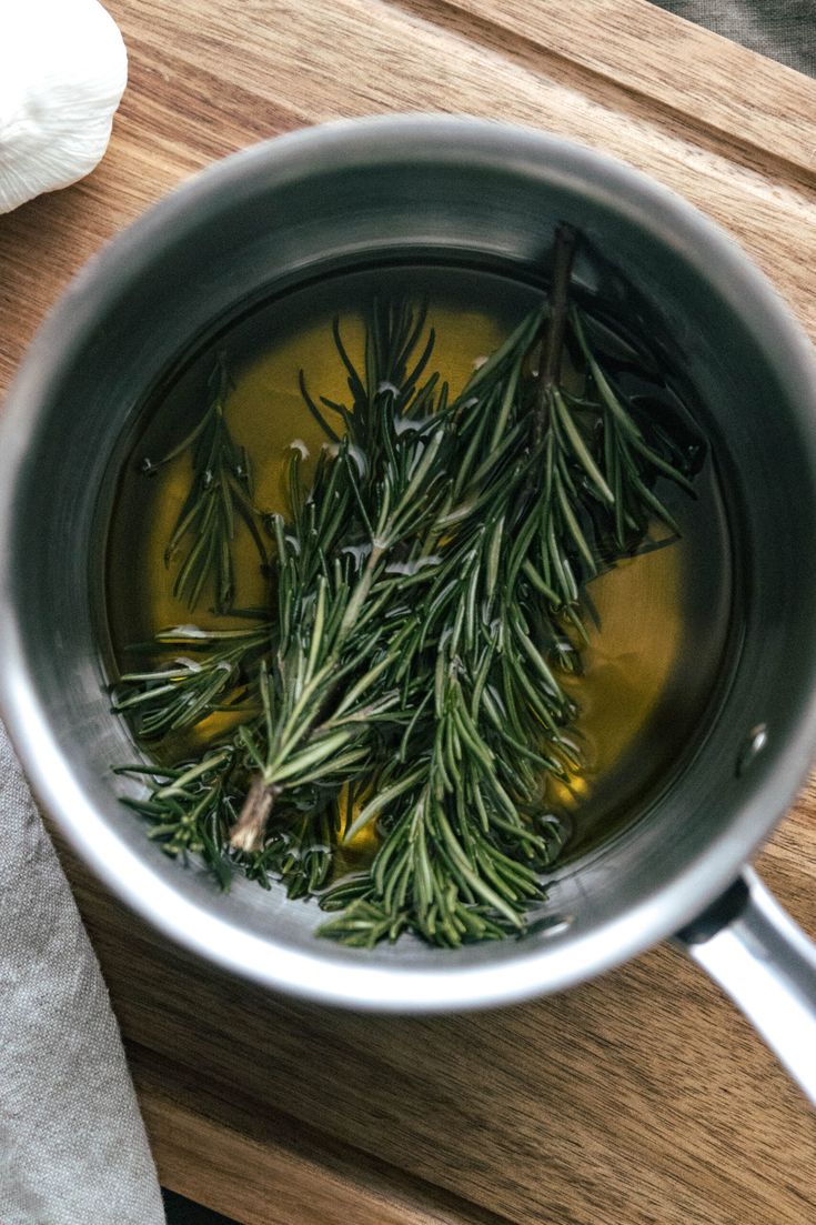 some herbs are cooking in a pot on a table