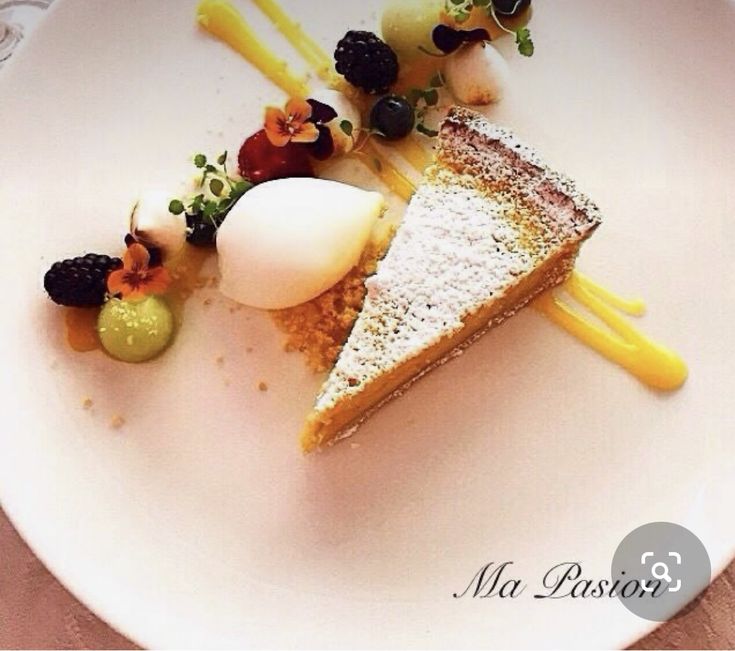 a white plate topped with a piece of cake covered in powdered sugar and fruit