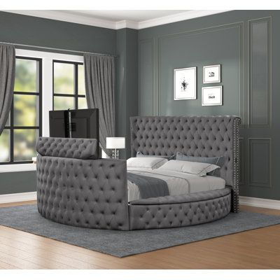 a bedroom with gray walls and furniture in the room, including a large bed that has an upholstered headboard