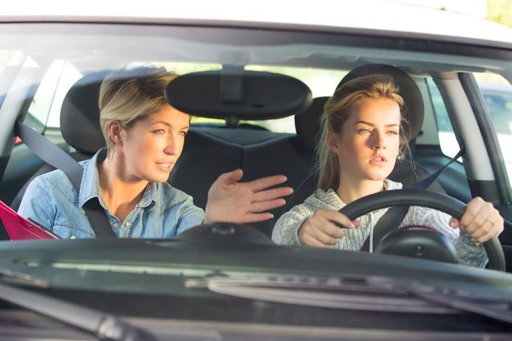 two women sitting in the driver's seat of a car talking to each other