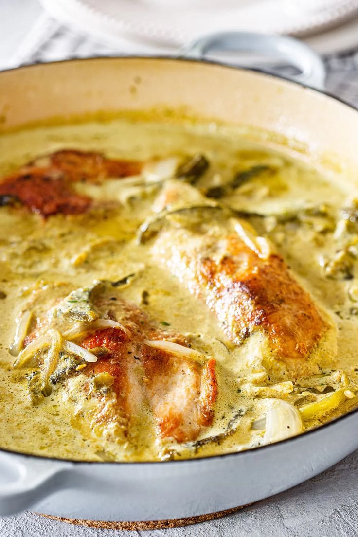 a pan filled with chicken and spinach soup on top of a white table cloth