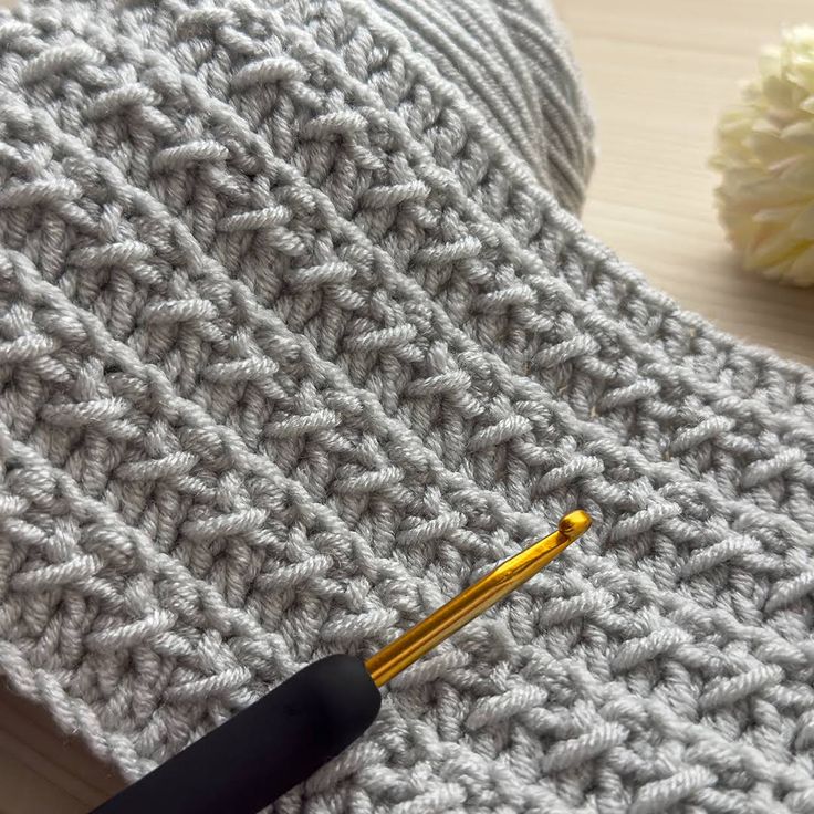 a crocheted blanket with a knitting needle next to it