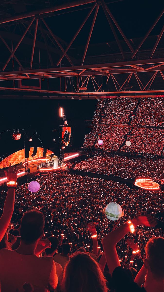 a large crowd at a concert with lights on the stage and people in the audience