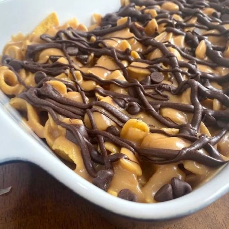 a white dish filled with chocolate and macaroni salad on top of a wooden table