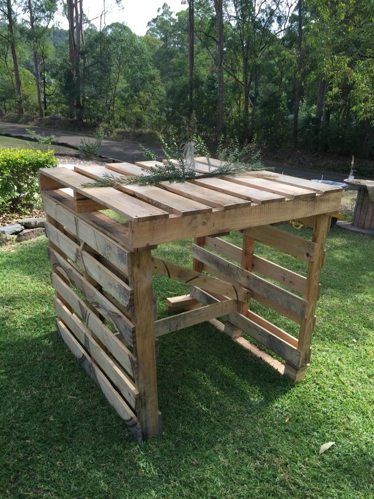 a table made out of wooden pallets in the grass with plants growing on top