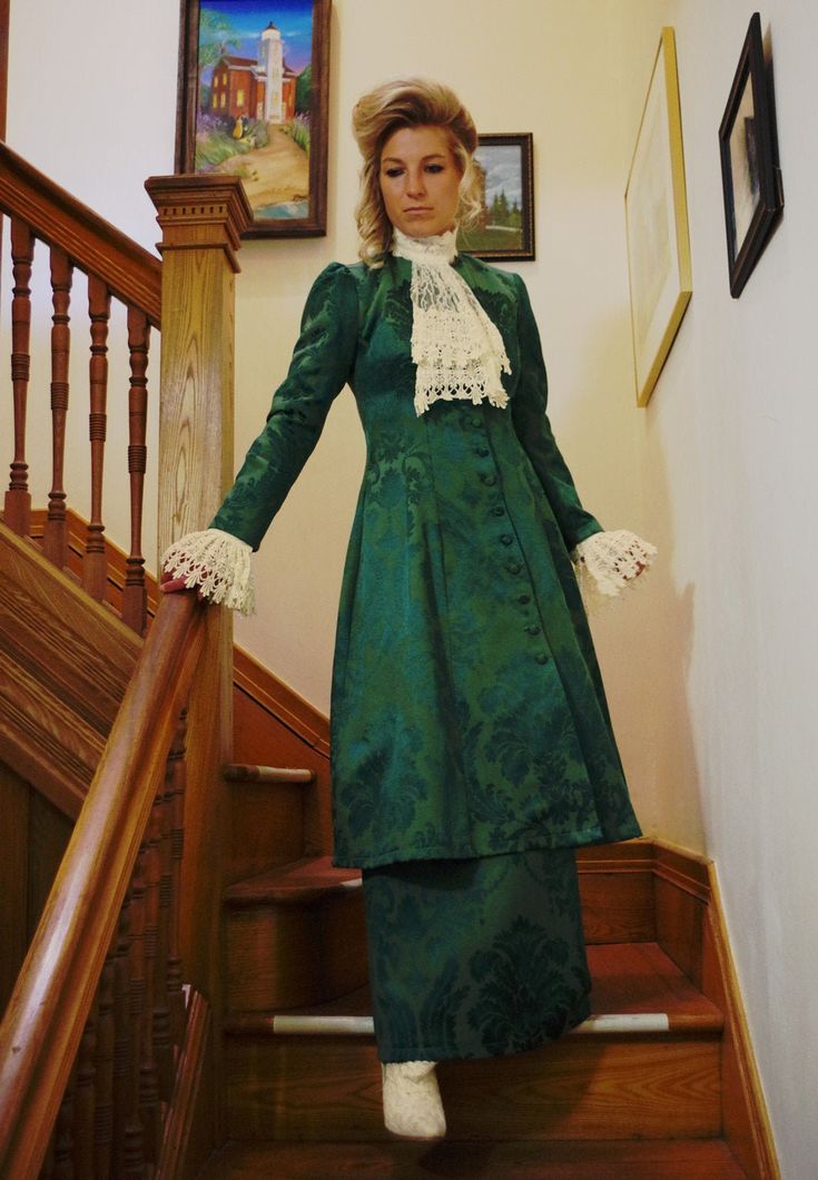 "Edwardian styled damask suit includes the long coat, skirt, and detachable jabot and cuffs. The coat measures approximately 44\" from shoulder to hem and closes with covered buttons. The matching skirt has an elastic waist. Proudly made in the US by Recollections. Damask fabric is 70% cotton & 30% polyester. Dry clean. Liesa completes the look with boots and jewelry and they are available priced separately. The following are approximate finished measurements and include room for ease of mov Elegant Victorian Brocade Dress For Costume, Elegant Brocade Victorian Dress For Costume, Formal Fitted Victorian Dress With Long Sleeves, Formal Long Sleeve Victorian Dress, Elegant Victorian Brocade Dress With Historical Design, Fitted Outerwear With Historical Design For Formal Occasions, Elegant Green Victorian Costume Dress, Elegant Green Victorian Dress For Costume Party, Regency Style Fitted Long Sleeve Outerwear