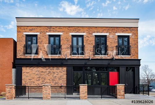 an old brick building with black shutters and red door