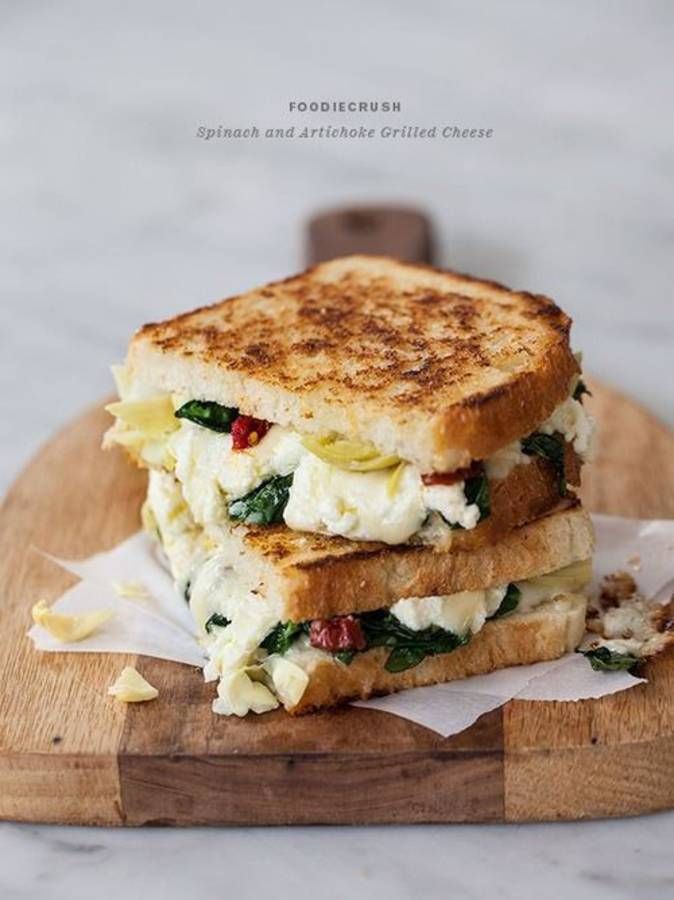 two grilled sandwiches stacked on top of each other with cheese and spinach in the middle