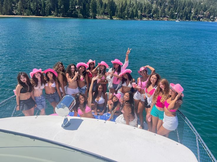 a group of women in bathing suits posing on a boat at the water's edge