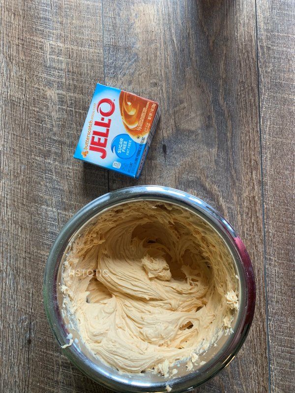 a bowl filled with peanut butter next to a carton of jello on top of a wooden table