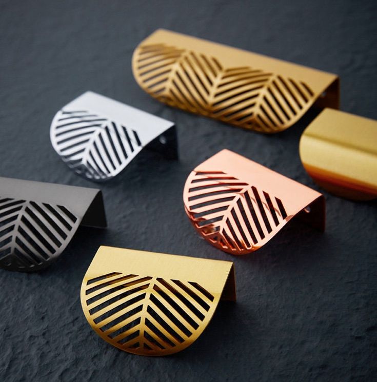 four different types of gold, silver and black paper clips on a dark table top