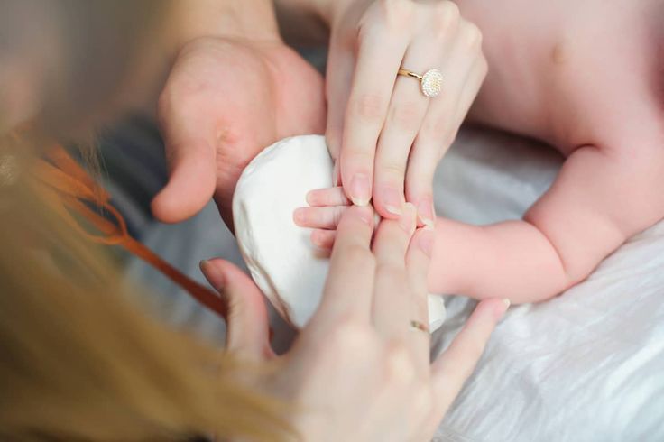 a woman holding a baby in her arms while she holds it up to the man's hand