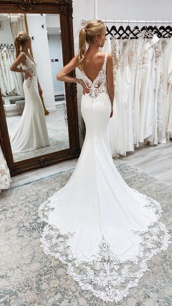 a woman standing in front of a mirror wearing a wedding dress