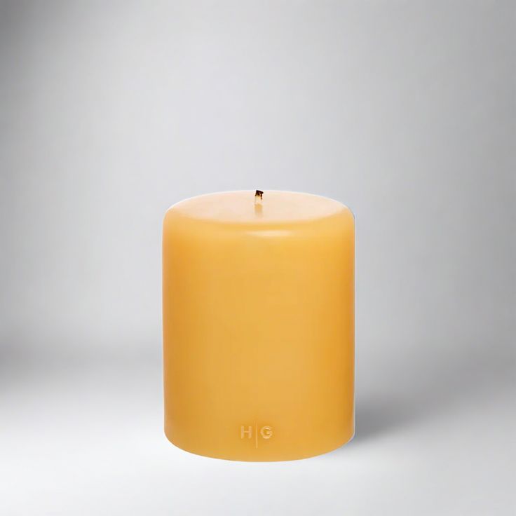 a yellow candle with the word h e on it's front and back side