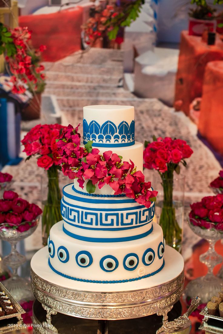 a white and blue cake with red flowers on top