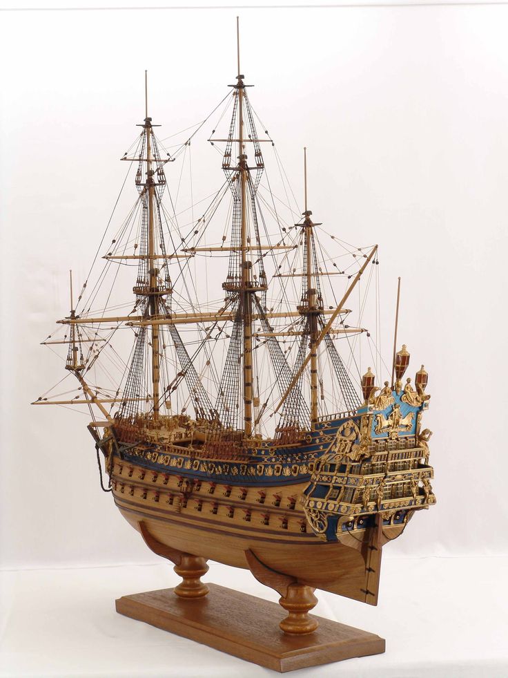 a wooden model of a sailing ship with sails and masts, on a white background