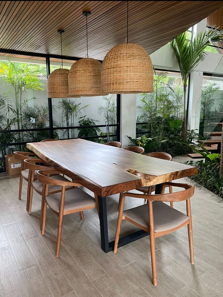 a dining room table and chairs with plants in the background