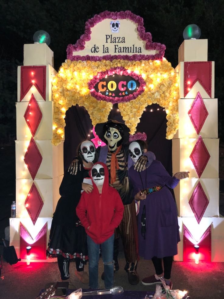 three people standing in front of a sign with skeletons on it and lights behind them