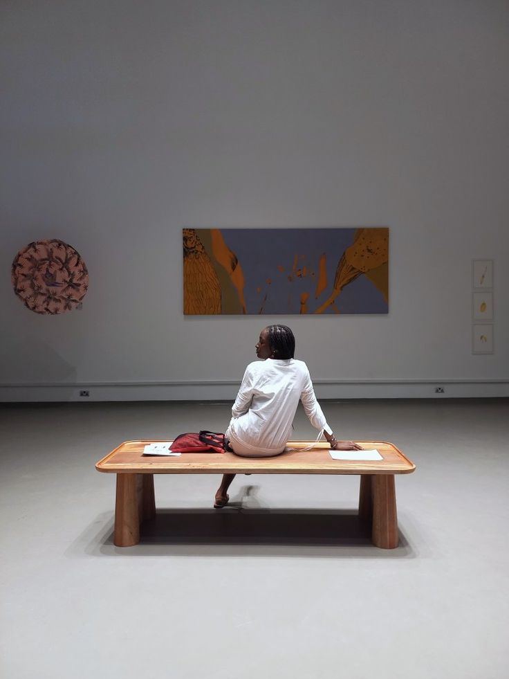 a person sitting on a bench in an art gallery