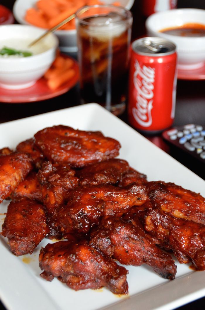 a white plate topped with chicken wings next to coca cola