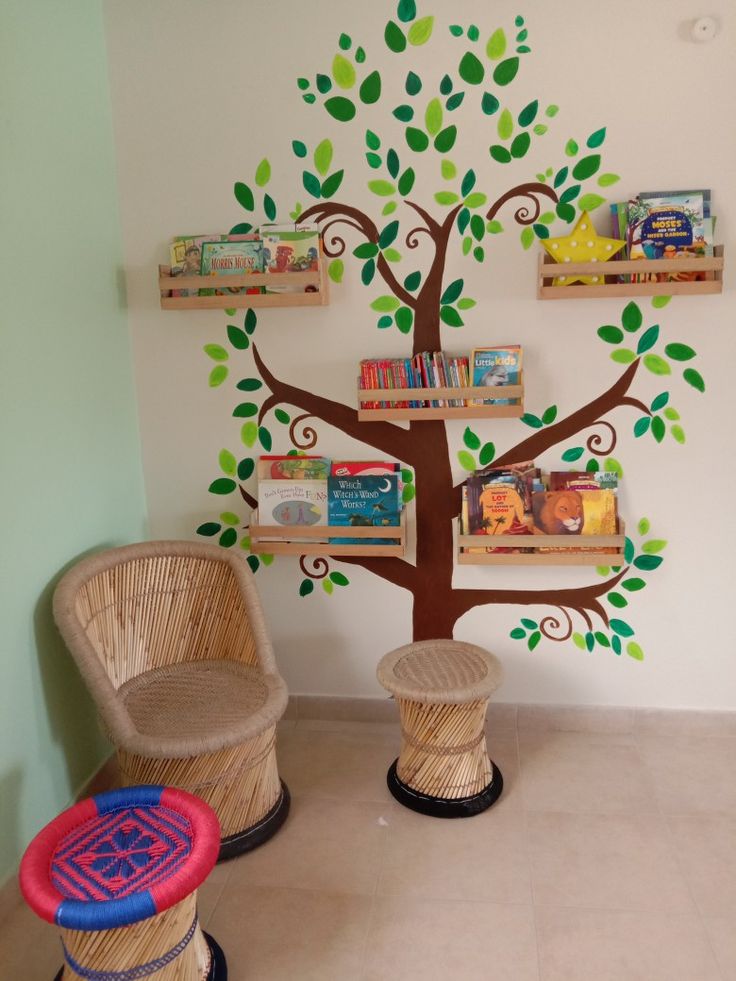 two wicker chairs sitting in front of a tree with books on shelves above it