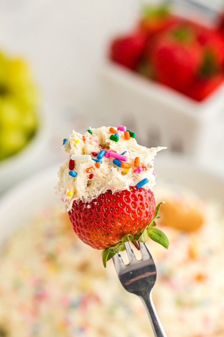 a fork with some food on it and strawberries in the bowl next to it