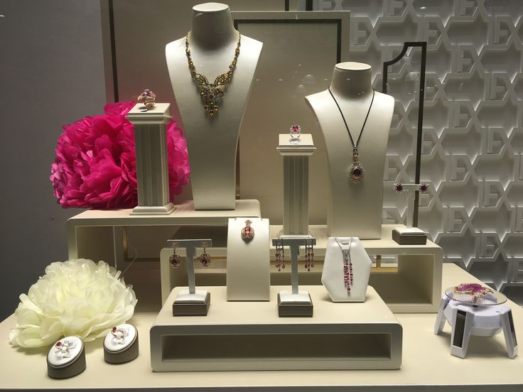 there are many necklaces on display in the store, including one with a pink flower