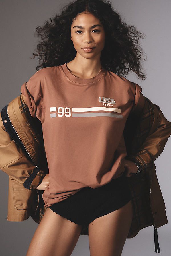 Hot off the press: laidback tees with gotta-have graphics. | Tennis Short-Sleeve Graphic T-Shirt by Back When in Red, Women's, Size: Smallmall, Cotton at Anthropologie Brown T-shirt For Fall Streetwear, Sporty Brown Cotton Tops, Casual Brown T-shirt With Graphic Print, Brown Relaxed Fit Tops With Text Print, Urban T-shirt With Screen Print For Fall, Casual Graphic Print T-shirt For Fall, Urban Style Short Sleeve T-shirt For Fall, Sporty Brown Short Sleeve Top, Sporty Brown Cotton T-shirt