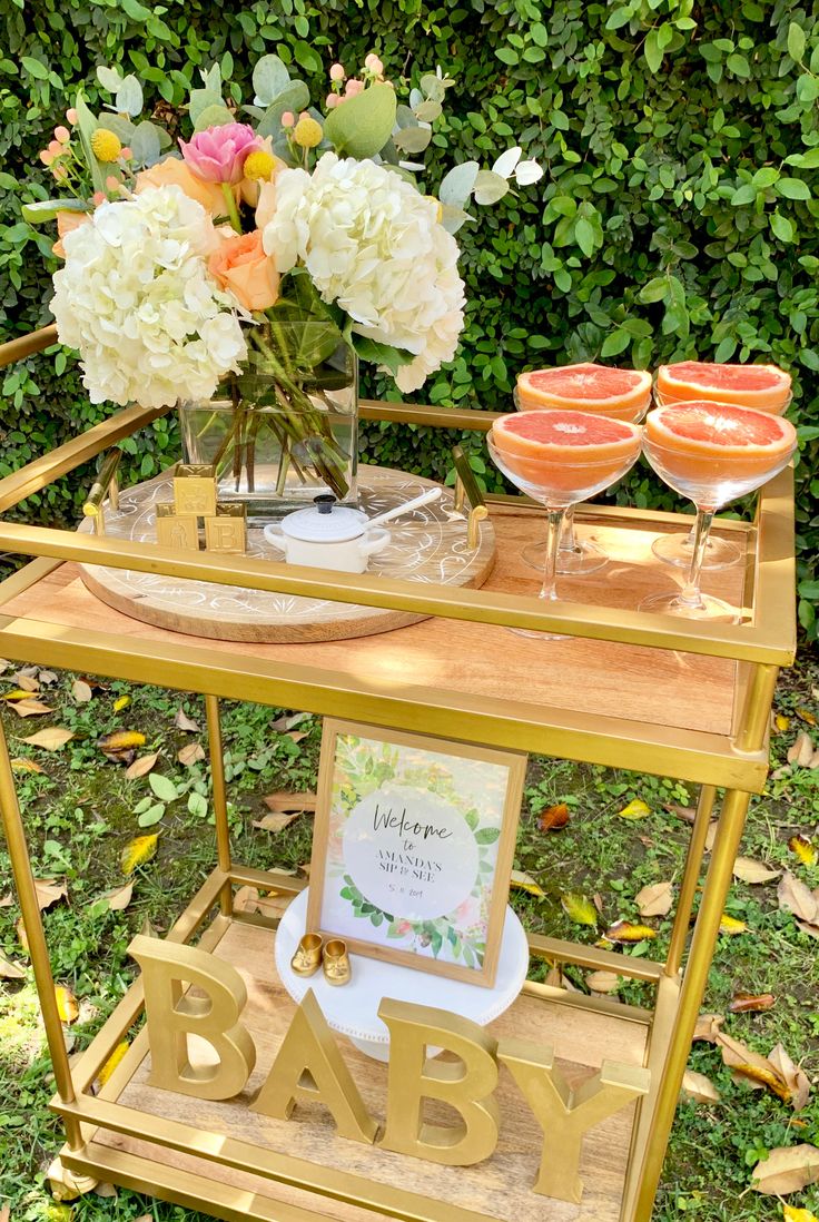 a gold bar cart with flowers and baby's names on it in the grass