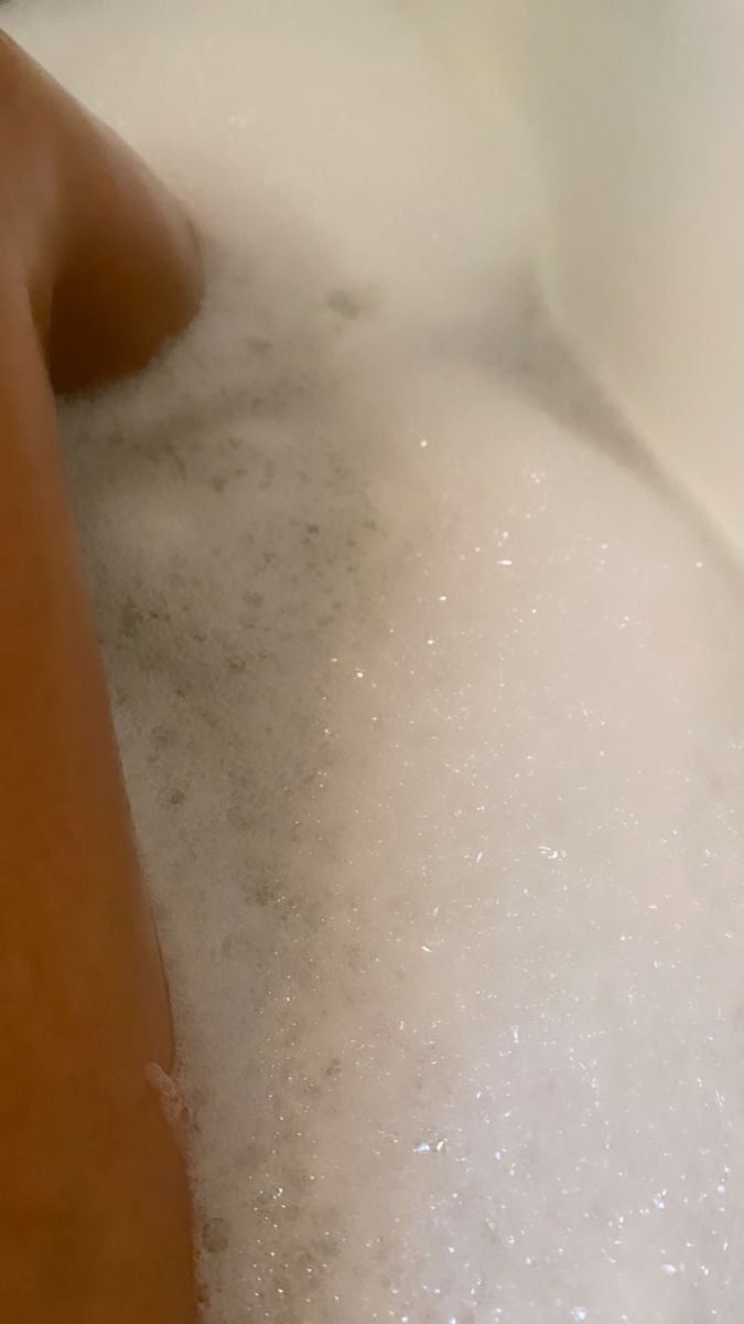 a person laying down in a bathtub filled with foam