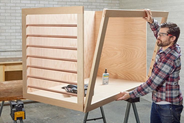 a man standing in front of a wooden cabinet with tools on it and another person behind him