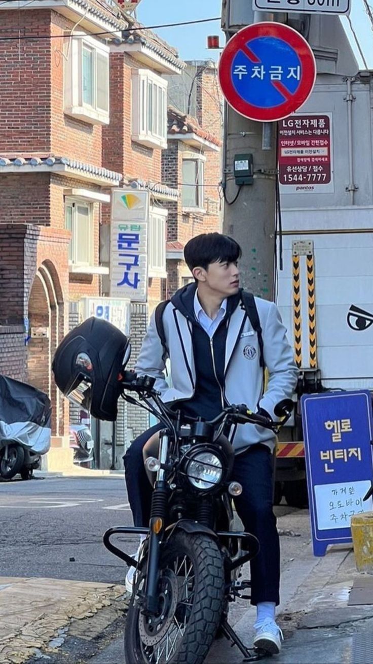 a man sitting on a motorcycle next to a street with no parking signs in the background