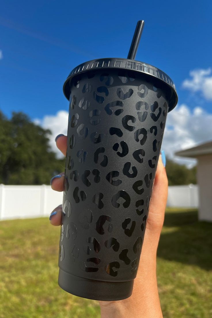 a hand holding a black cup with a straw in it