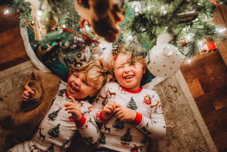 two children laying on the floor in front of a christmas tree