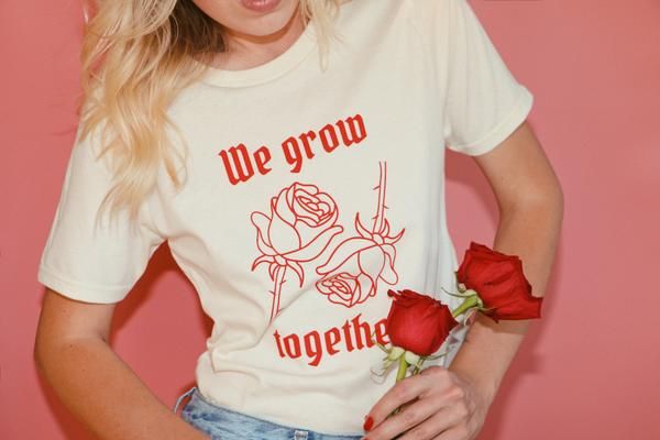 a woman wearing a t - shirt that says we grow together with roses on it