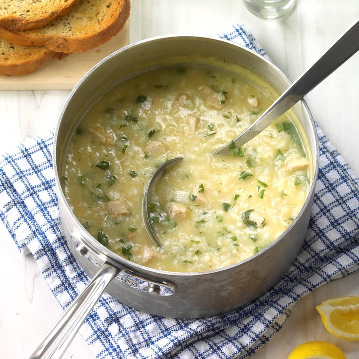 a pot filled with soup next to sliced lemons and bread on a white table