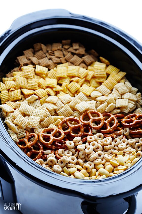 a crock pot filled with cereal and pretzels