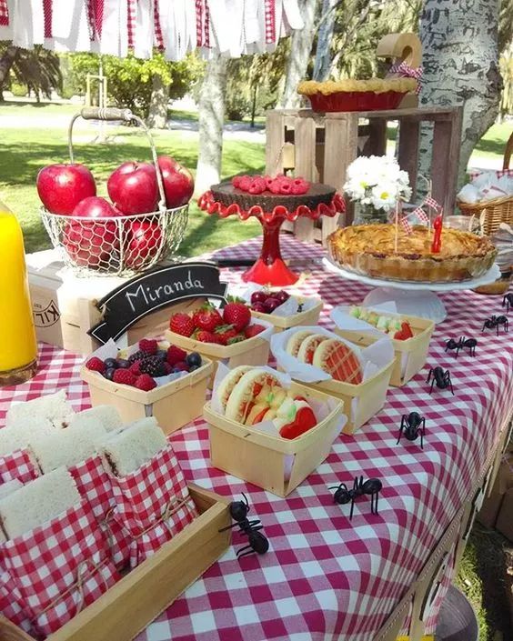 an outdoor picnic with fruit and pastries on the table, along with other food items