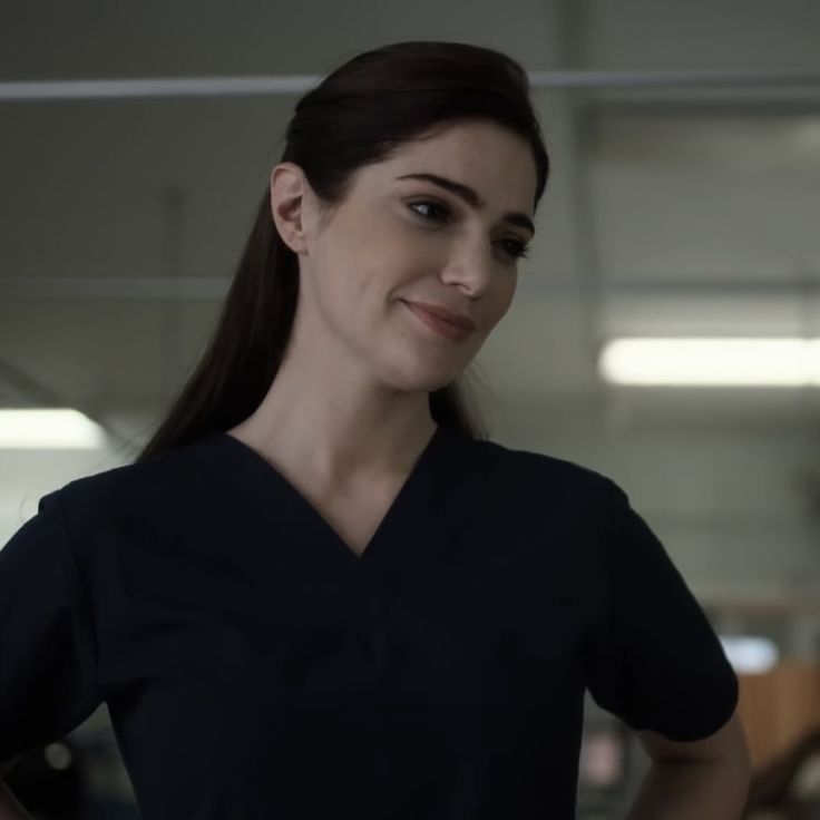 a woman with long hair wearing a black scrub top and standing in an office building