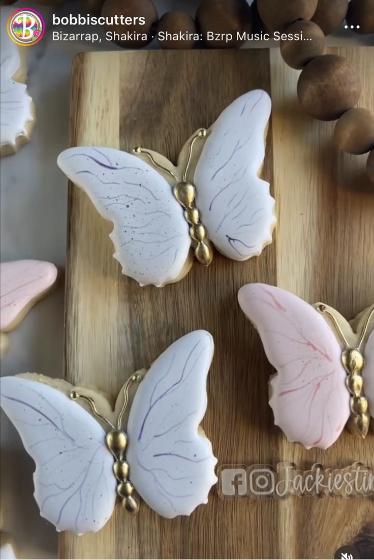 three butterfly shaped cookies sitting on top of a wooden cutting board